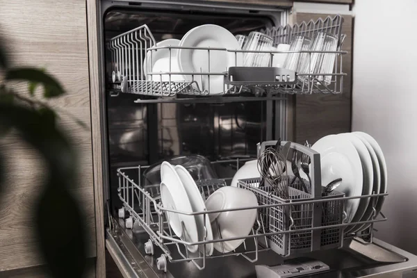 Open dishwasher with clean utensil inside, cutlery, glasses, dishes at kitchen — Stock Photo, Image