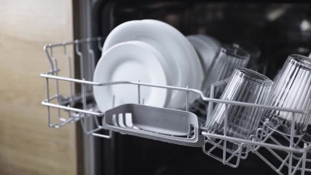 Kadın eli, mutfak bulaşık makinesi dolu sepeti yerleştirir ve yerleştirir. — Stok video