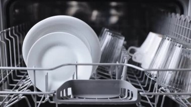 Kadın elleri bulaşık makinesi sepeti yerleştirir, kirli tabağı açık makineye koyar.