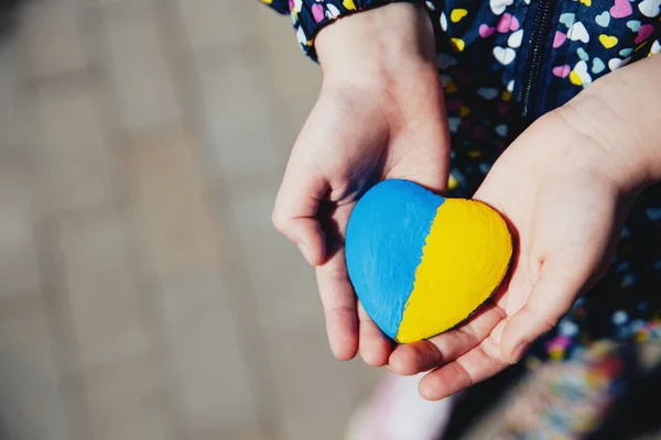 우크라이나 국기나 국가가 새겨진 하트 모양의 돌을 들고 있는 작은 아이 — 스톡 사진
