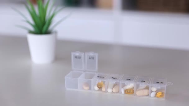 Hand sätta piller till medicinska piller låda, tablettdoser för dagligt intag, droger, kapslar — Stockvideo