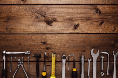 Ahşap arka planda çalışma masasının üzerinde çeşitli iş aletleriyle yatıyordu. Tamir için yeni el aletinin üst görüntüsü, inşaat seti, genel giderler. Erkekler için olmalı. İnşaat için ekipman. Endüstri kavramı