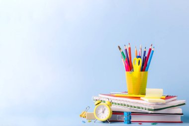 Birçok farklı okul, ofis malzemeleri ve kırtasiye malzemeleri. Okul konseptine geri dönelim. Defter, kitap, kalem, makas, çalar saat, saat, saat yeşil arka plandaki ahşap bir masanın üzerindeki çıkartma standı..