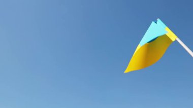 Ukraine national flag in human hand waving by wind in front of clear blue sky. Small blue-yellow symbol souvenir of nation, freedom, nationality, strength, will and honor. High quality FullHD footage