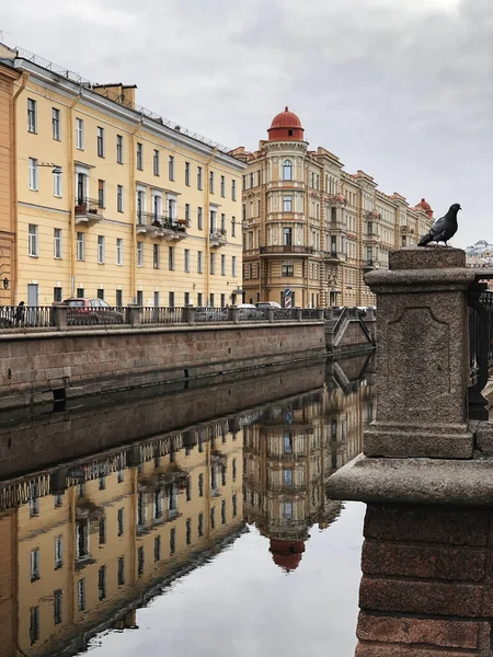 Açık sarı tarihi bir bina su yüzeyine yansıyor..