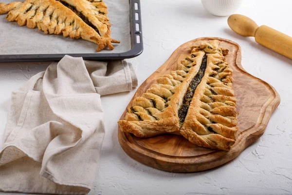 Puff pastry pie with cheese and spinach in shape of  Christmas tree on baking sheet.