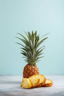 Pastel mavi arka planda dilimlenmiş ananas. Boşluğu kopyala.