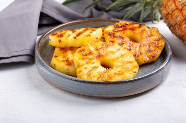 Beton arka planda gri tabakta ızgara ananas dilimleri..