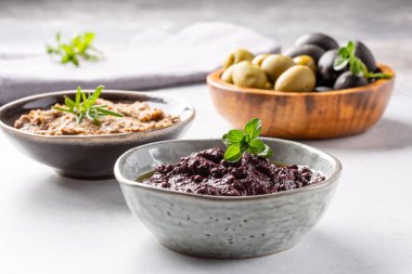 Tapenade - zeytinden yapılmış macun. Beton zemin üzerinde yayılabilir siyah ve yeşil zeytin kremi olan kaseler. 