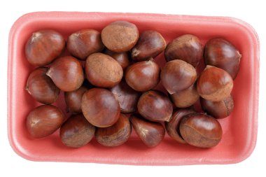 Pembe köpüklü yemek tepsisinde taze çiğ, yenilebilir tatlı kestaneler. Beyaza izole edilmiş. Üst Manzara. Yakın plan..