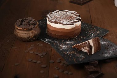 Koyu arkaplanda farklı çikolata katmanları olan lezzetli kremalı pasta.