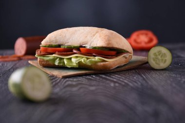 Kelebekli sandviç (baharatlı sosis) ve ahşap arka planda salata.