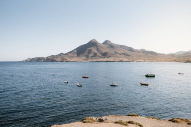 Güneşli bir yaz gününde arka planda deniz manzarası, botlar, dağlar. La Isleta del Moro, Cabo de Gata, Almeria, İspanya.