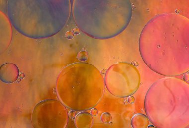 Açık turuncu ve suyun üzerinde yüzen yağ damlasının pembe renklerinin soyut arkaplanı