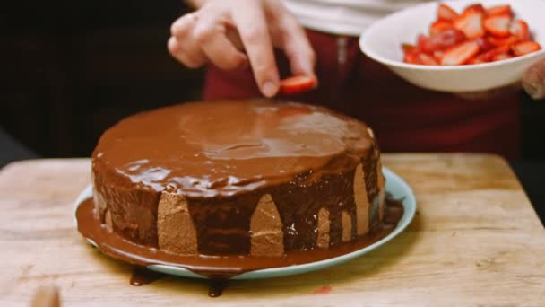 Eu decoro o bolo de chocolate com morangos. 4k vídeo — Vídeo de Stock