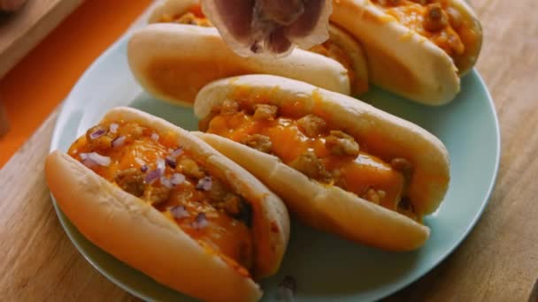 Pressione cebola vermelha sobre chili queijo Hot Dogs. 4k vídeo — Vídeo de Stock