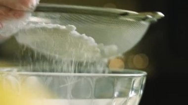 Paslanmaz çelik elek aracılığıyla pudra şekeri veriyorum. Ev yapımı zencefilli kurabiye için krema hazırlıyorum.