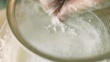 Paslanmaz çelik elek aracılığıyla pudra şekeri veriyorum. Ev yapımı zencefilli kurabiye için krema hazırlıyorum.