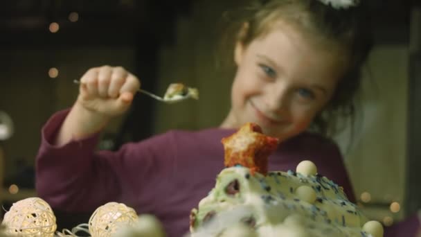 A menina está comendo bolo com massa verde, cerejas azedas e creme azedo. Ele também tem ornamento de comida e o bolo de estrela vermelha — Vídeo de Stock