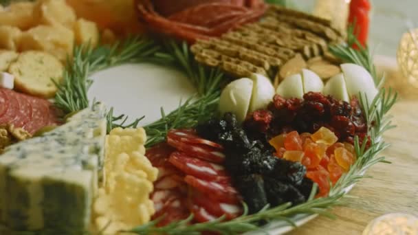 Charcuterie plate with salami, different kinds of cheese. It has dried fruits, various nuts and honey. Holiday arrangement with burning candles — Stock Video