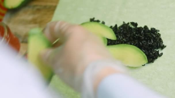 Mettere pezzi di avocado sul burrito di sushi — Video Stock