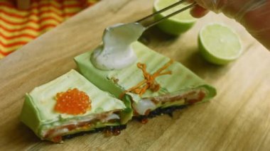 Suşi burritolarına çatalla yoğurt sosu ekliyorum.