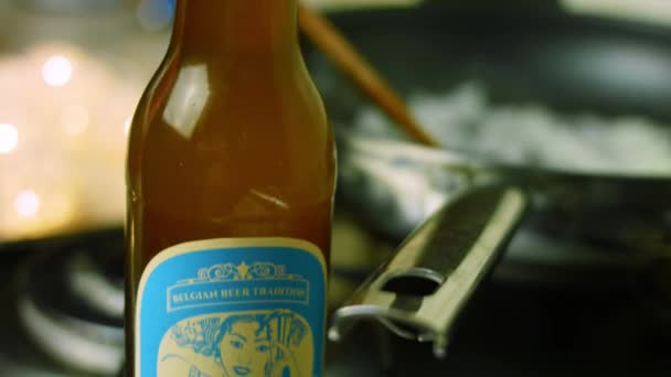 Mezclar la cebolla picada y freír en la sartén. Una botella de cerveza belga en el fondo — Vídeos de Stock