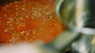 Chili Con Carne 'ın tüm malzemelerini tavada kızart. Ateşe bir tencere ekliyorum.