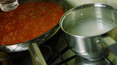Uzun kaynayan pirincin üzerine bir bardak su ekliyorum. Arka planda, chili con carne pişir. Makro çekim