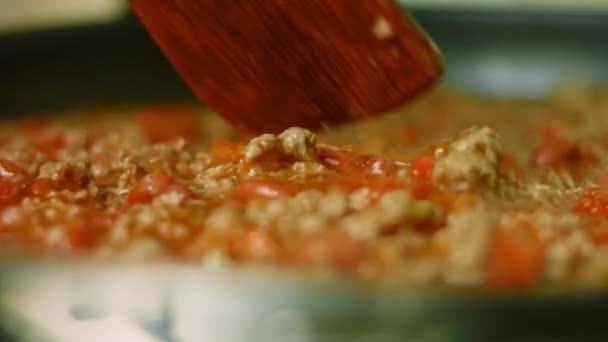 Mezclar todos los ingredientes con una cuchara de madera. Cocinar chile con carne, cocina mexicana. Disparos macro — Vídeo de stock