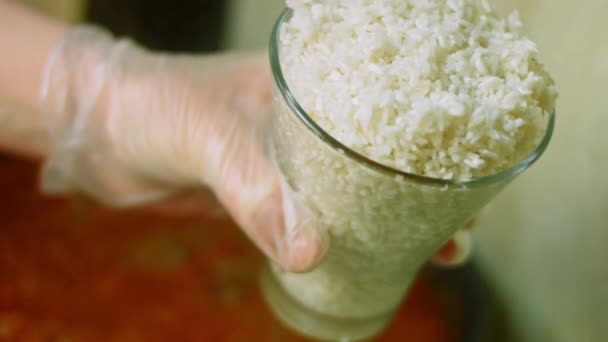 Προσθέτω ένα μεγάλο ποτήρι ρύζι για να βράσει. Στο παρασκήνιο, μαγειρέψτε τσίλι con carne — Αρχείο Βίντεο