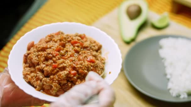 Ik heb chili con carne op een bord naast rijst gelegd. Het wordt gekookt van kalkoen en Belgisch bier — Stockvideo
