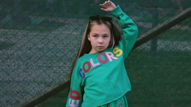 La niña es una modelo profesional posando. Cancha de baloncesto en segundo plano — Vídeos de Stock