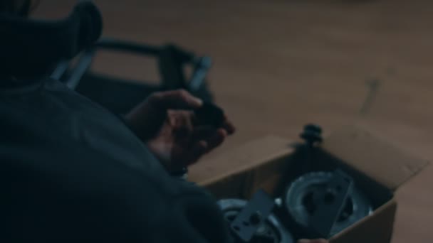 Πλευρική άποψη ενός αμερικανού εργάτη σε εργαστήριο σε εργοστάσιο κατασκευής αναπηρικών αμαξιδίων, που κάθεται σε πάγκο εργασίας χρησιμοποιώντας εργαλεία χειρός και συναρμολογώντας μέρη ενός προϊόντος, που κάθεται σε αναπηρικά αμαξίδια — Αρχείο Βίντεο