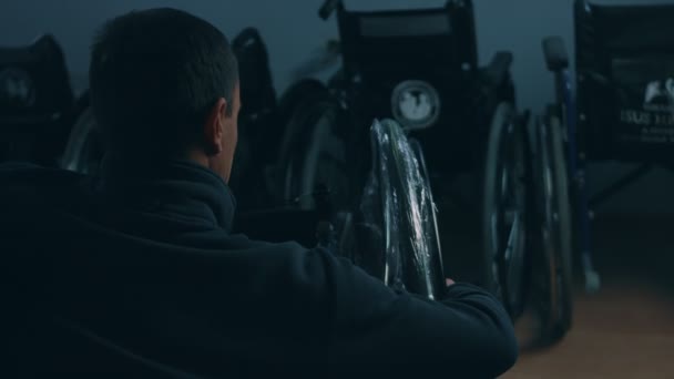 Side view of one American male workers in a workshop at a factory making wheelchairs, sitting at a workbench using hand tools and assembling parts of a product, sitting in wheelchairs — Stock Video