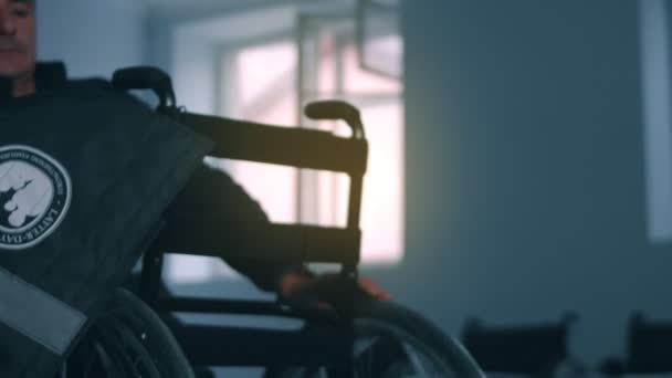 Vista lateral de um trabalhador americano em uma oficina em uma fábrica de cadeiras de rodas, sentado em uma bancada de trabalho usando ferramentas manuais e montando partes de um produto, sentado em cadeiras de rodas — Vídeo de Stock