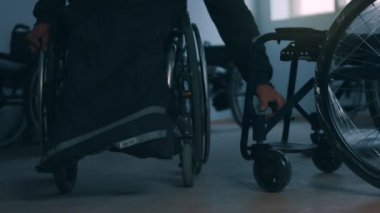 Tekerlekli sandalye üreten, el aletleri kullanan ve bir ürünün parçalarını birleştiren, tekerlekli sandalyede oturan bir fabrikada çalışan Amerikalı erkek işçinin yan görüntüsü.