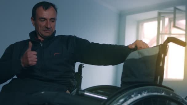 Zijaanzicht van een Amerikaanse mannelijke arbeider in een werkplaats in een fabriek die rolstoelen maakt, op een werkbank zit met handgereedschap en delen van een product monteert, in rolstoelen zit — Stockvideo
