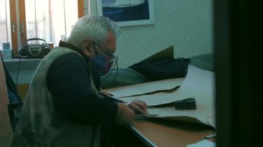 Adam dikiş makinesini makasla kesiyor.