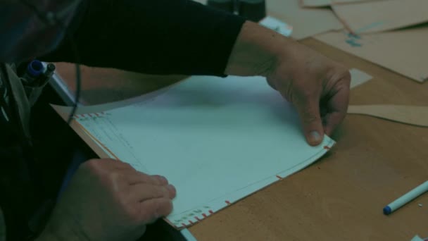 De baard tekent het model om kleding te naaien met een liniaal en een potlood — Stockvideo