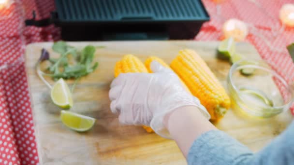 Engrasar con aceite y poner en la parrilla tres plantas de maíz — Vídeo de stock