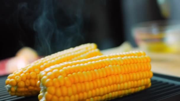 Smörj med olja och lägg på grillen tre majsplantor. Makrofotografering — Stockvideo