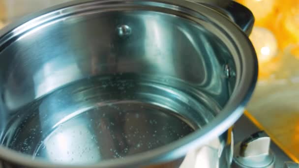 Koka vatten i en skål. Bredvid finns en vacker flaska vin — Stockvideo