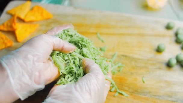 Ik hou in mijn handen een groene pesto kaas in kleine stukjes gesneden. — Stockvideo