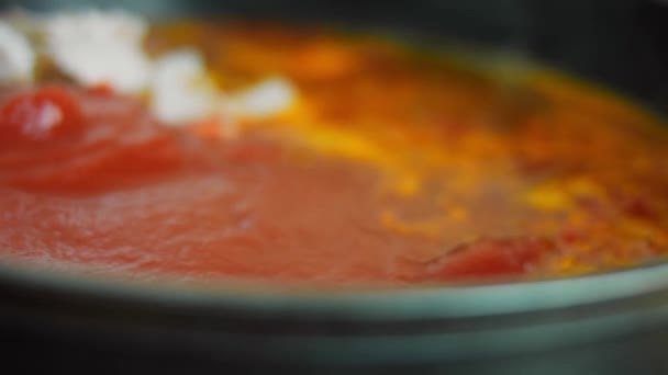 Jag tillsätter konserverade tomater till ingredienserna till den stekta mexikanska soppan. Makrofotografering — Stockvideo