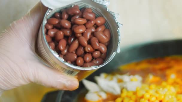 Добавить консервированные красные бобы в ингредиенты для жареного мексиканского супа — стоковое видео