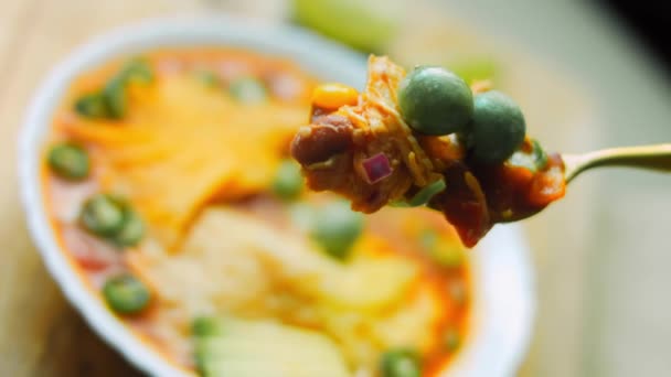 Sopa mexicana en una cuchara de oro. Sopa mexicana con tres tipos de queso. Sopa real con aguacate añadido y cacahuetes con vasabi. Uso séquito romántico y cuchara de oro. Disparos macro — Vídeo de stock