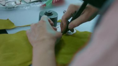 Deri atölyesinde dikiş makinesi çalışıyor. Elleri ayakkabı için deri detaylar üzerinde çalışıyor. Ayakkabı fabrikasında dikiş makinesiyle kadın eli makro çekim.