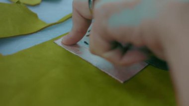 Deri atölyesinde dikiş makinesi çalışıyor. Elleri ayakkabı için deri detaylar üzerinde çalışıyor. Ayakkabı fabrikasında dikiş makinesiyle kadın eli makro çekim.