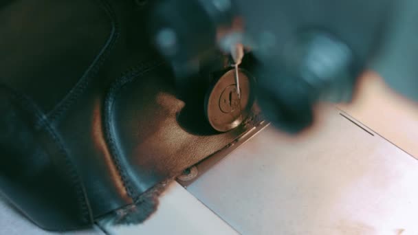 Symaskin i en läderverkstad i aktion med händer som arbetar med läderdetaljer för skor. Makro skott av kvinnors händer med symaskin på skor fabrik — Stockvideo